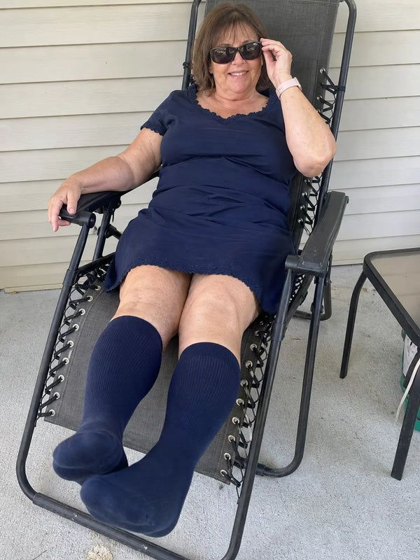 Older woman wearing navy knee high compression socks at home