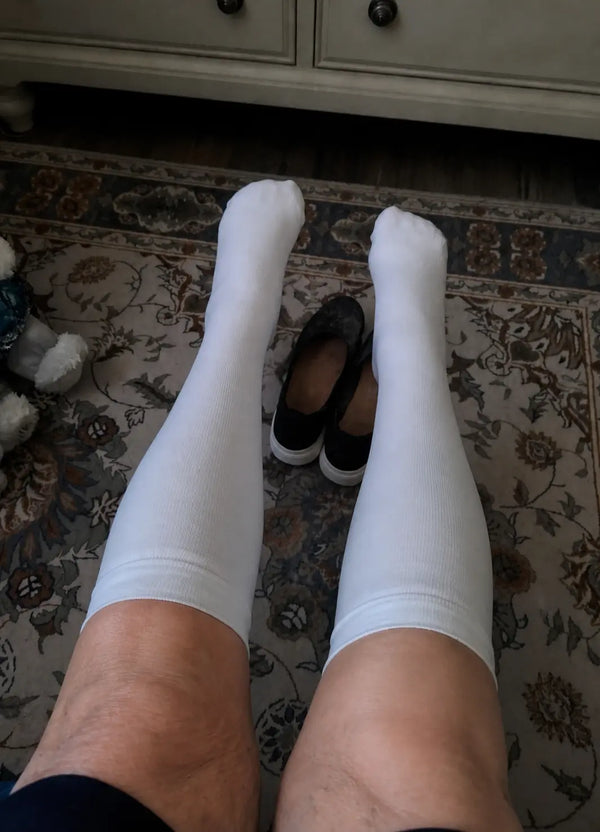 Older woman sitting in a chair wearing navy compression socks